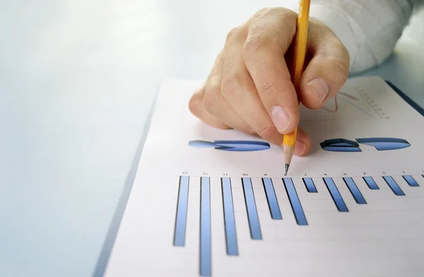 Hombre sosteniendo un lápiz trabajando en un gráfico — Foto de Stock