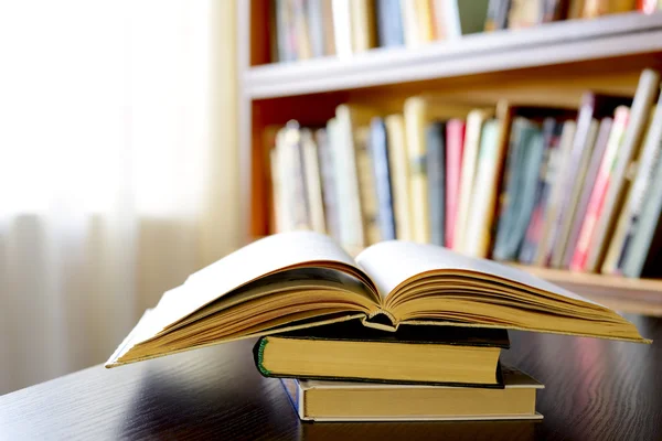 Ein offenes Buch mit Bücherregalen im Hintergrund — Stockfoto