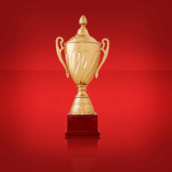Primo piano di un trofeo d'oro lucente, su rosso — Foto Stock