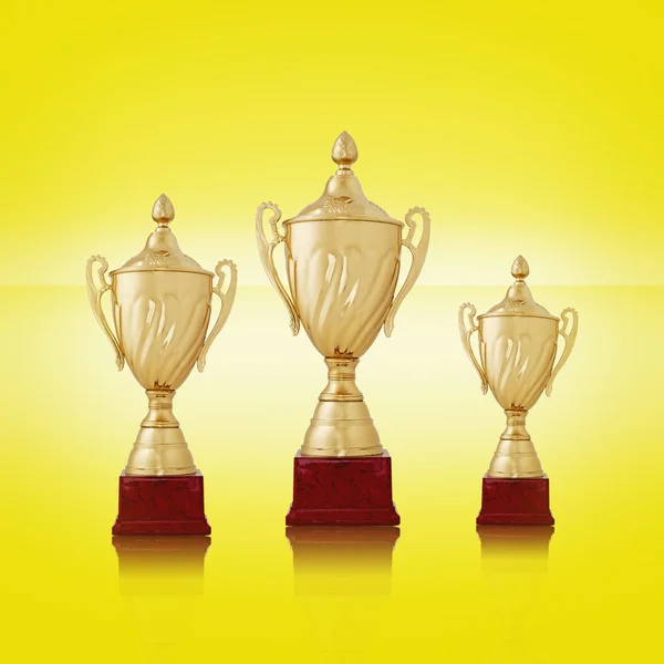 Three gold trophies on bright yellow background — Stock Photo, Image