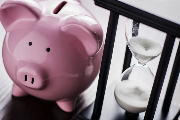 Piggy bank with an hour glass — Stock Photo, Image
