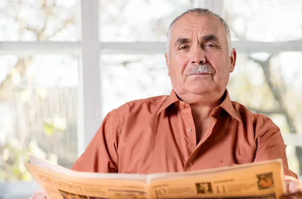 Friendly elderly man sitting reading — Stock Photo, Image