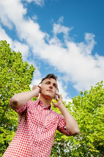 Giovane uomo godendo la musica nel parco — Foto Stock