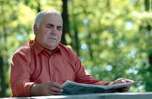 Starszy mężczyzna siedzący czytanie gazety — Zdjęcie stockowe