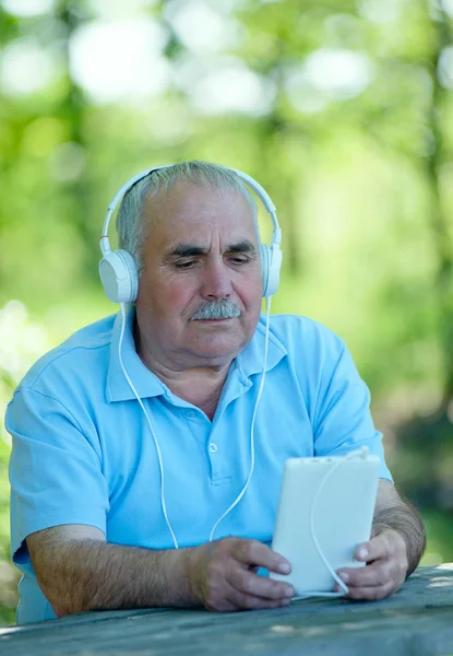 Uomo anziano alla ricerca di una melodia sul suo lettore MP3 — Foto Stock