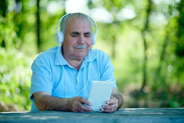 Senior man searching for a tune on his MP3 player — Stock Photo, Image