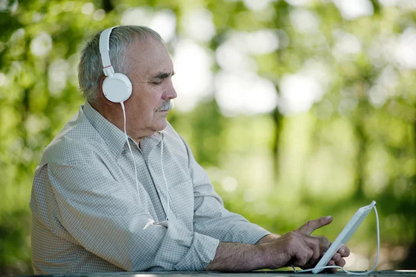 Elderly man listening to music on a tablet — Stock Photo, Image