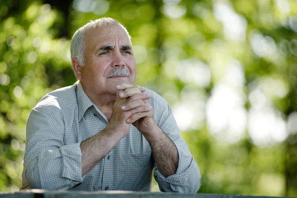Ηλικιωμένος άνδρας κάθεται στην σκέψη κήπων — Φωτογραφία Αρχείου
