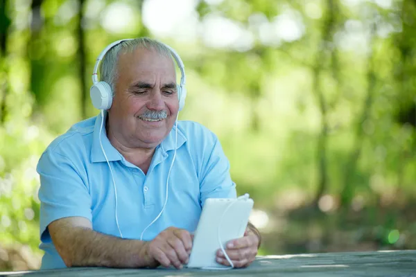 Старший чоловік шукає мелодію на своєму MP3 плеєрі — стокове фото