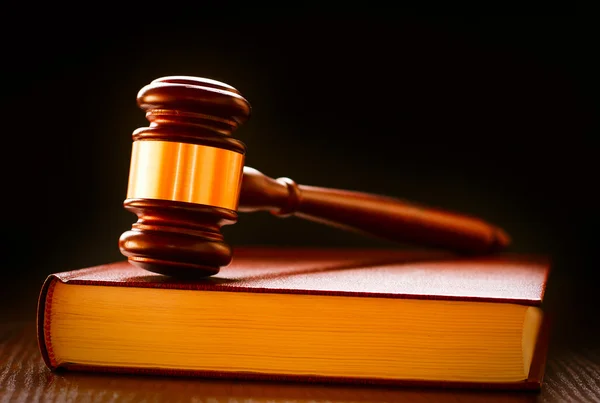 Giudici in legno e ottone martellano su un libro di leggi — Foto Stock