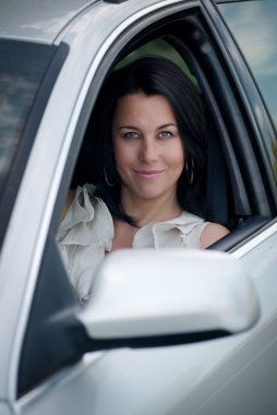 Güzel genç bir kadın araba kullanıyor.