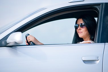 Güzel genç bir kadın araba kullanıyor.