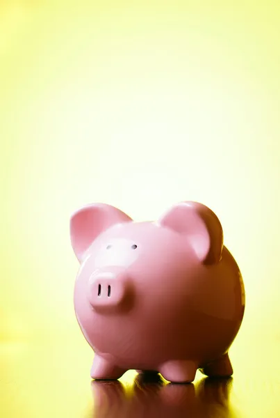 Pink piggy bank on a bright yellow background Royalty Free Stock Images