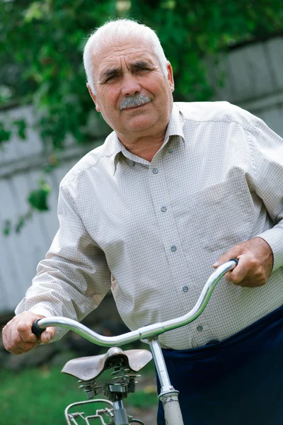 Senior man leaning on the handlebar of his bicycle — Stock Photo, Image