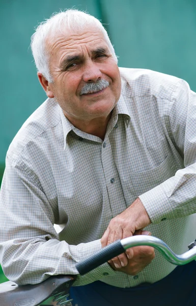 Senior man leaning on the handlebar of his bicycle — Stock Photo, Image