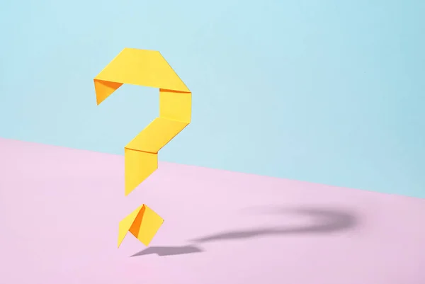 浮动的黄色折纸问号给粉色和蓝色的双色背景投下偏移阴影 并在概念图像中留有复制空间 — 图库照片
