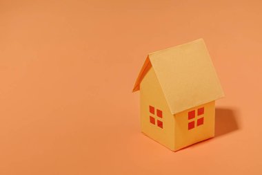 Fotokopi alanı olan turuncu kağıt ev. Satış yapma ve ev için kredi alma fikri. Asgari konsept ve pastel renk.