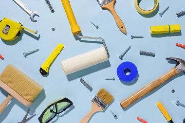 DIY, bakım ya da onarım çeşitli el aletleri ve boya fırçaları ile düz bir şekilde dizilmiş mavi üzerinde durgun yaşam