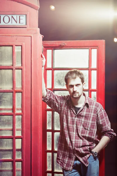 Young man standing at telephone box — Stock Photo, Image