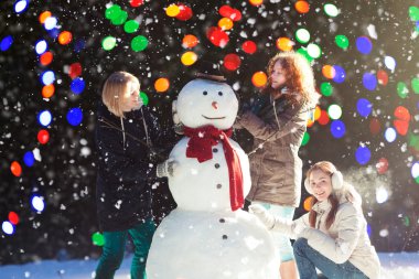 Three girls building a snowman