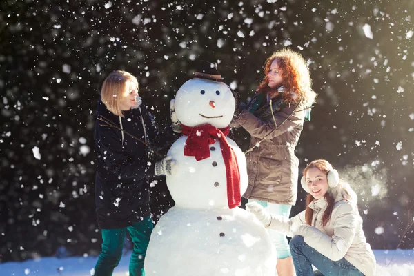 Trzy dziewczyny budowa snowman — Zdjęcie stockowe