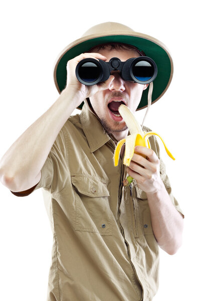 Explorer with binoculars eating banana