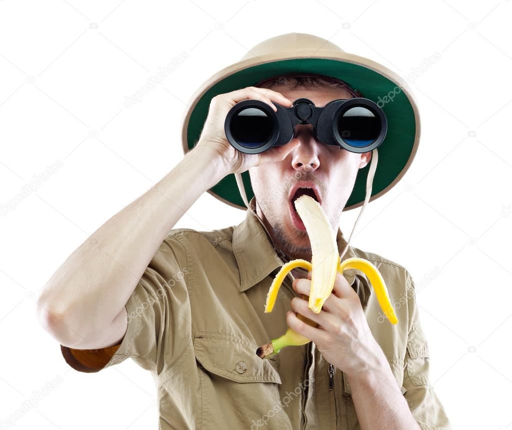 Explorer with binoculars eating banana