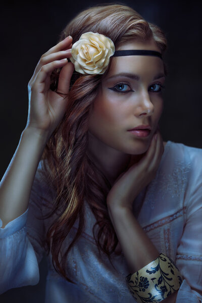 Glamour hippie girl posing on dark background, toned low key portrait