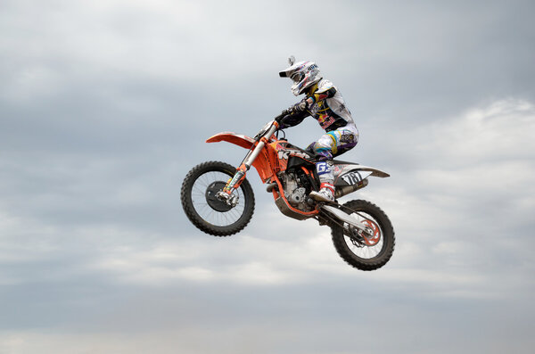 MX racer performs a jump in background of clouds