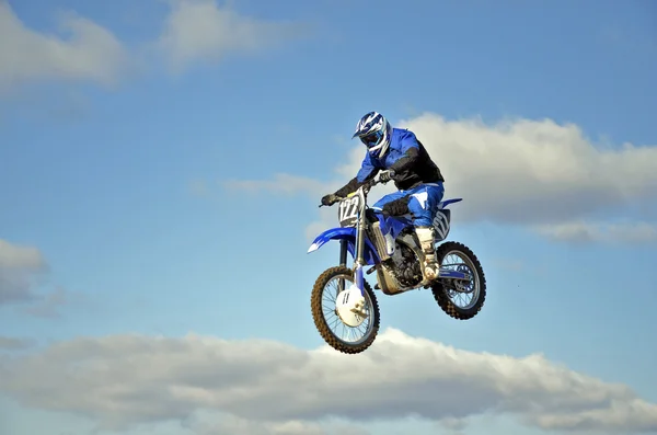 Voo de motocross motociclista contra o céu azul e nuvens — Fotografia de Stock