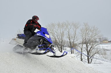 On the snowmobile rider jumps down the mountain clipart