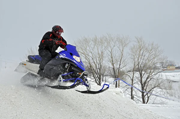 On the snowmobile rider jumps down the mountain — Stock Photo, Image