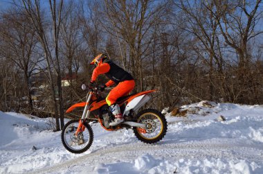 MX winter motocross racer on a motorcycle arrives on a snowy hil clipart