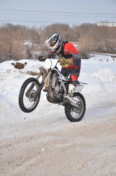 Motocross rider en una motocicleta de conducción en invierno carretera holding u —  Fotos de Stock