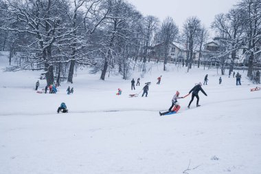 Sibiu, Romanya - 12 Ocak 2019. Kış zamanı kar üzerinde oynayan bir grup çocuk ve yetişkin.