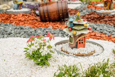 Garden arrangement with wood logs, wicker baskets, gravel and various ornaments