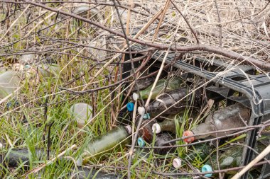 glass bottles in container with plastic caps thrown in nature