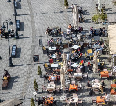 Sibiu City, Romania - 15 April  2022. Outdoor terrace with tables and chairs, aerial top view People sitting and eating together near Sibiu old city center