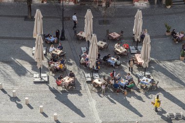 Sibiu City, Romania - 15 April  2022. Outdoor terrace with tables and chairs, aerial top view People sitting and eating together near Sibiu old city center