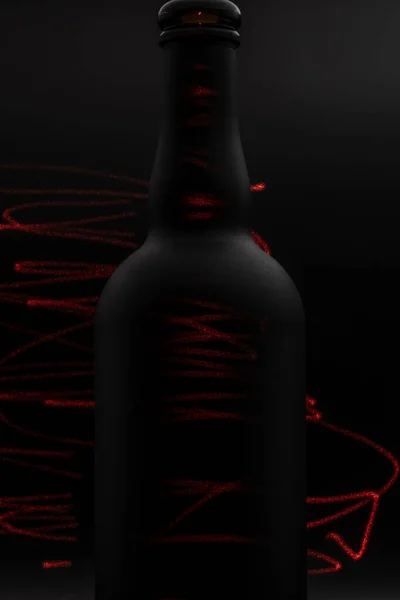 matte black wine bottle with red laser lines painting on dark background