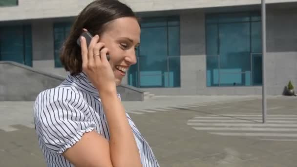 Woman walking at the street and talking on mobile phone — Stockvideo