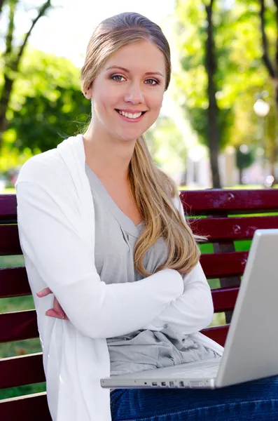 Студент с ноутбуком сидит на скамейке — стоковое фото