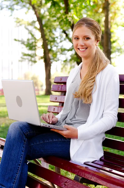女人坐在长凳上用的笔记本电脑 — 图库照片