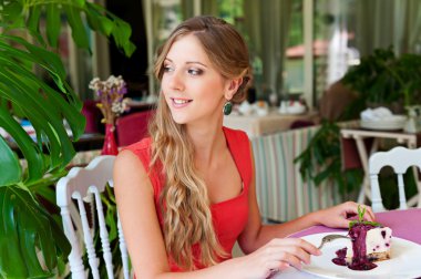 Cafe'de oturan ve pasta yiyen kadın