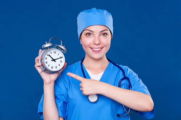 Smiley verpleegster wijzend op alarm clock — Stockfoto