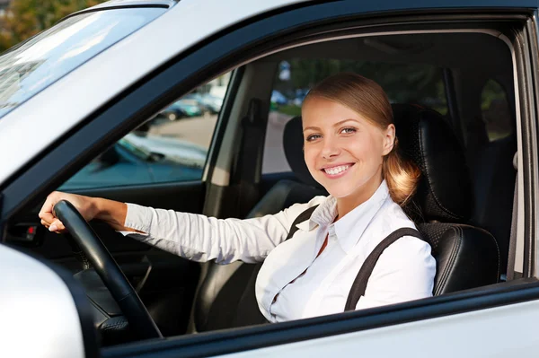Женщина водит машину и улыбается — стоковое фото
