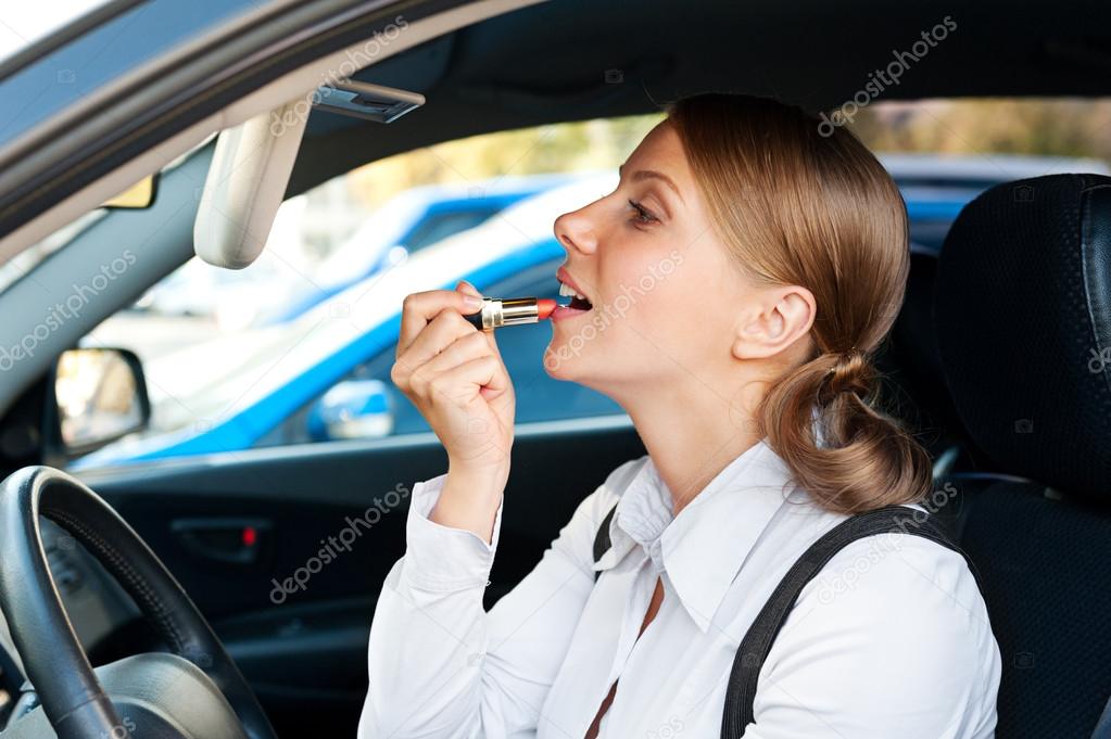 woman sitting in the car and painting her lips