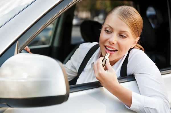 Frau schminkt sich die Lippen und fährt Auto — Stockfoto