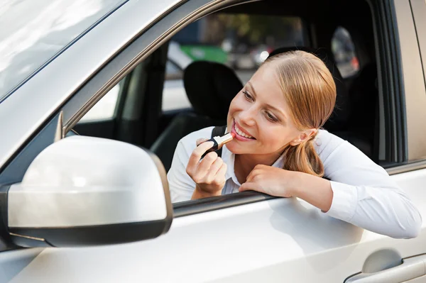 Woman looking at mirror and painting her lips — Stock Photo, Image