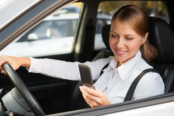 Zakenvrouw zittend in de auto en schrijven sms — Stockfoto